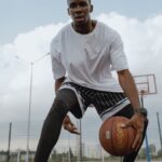 A focused athlete dribbles a basketball on an outdoor court, embodying fitness and agility.