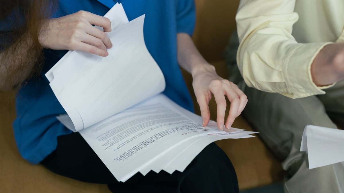 People in professional attire reviewing important documents together on a sofa.