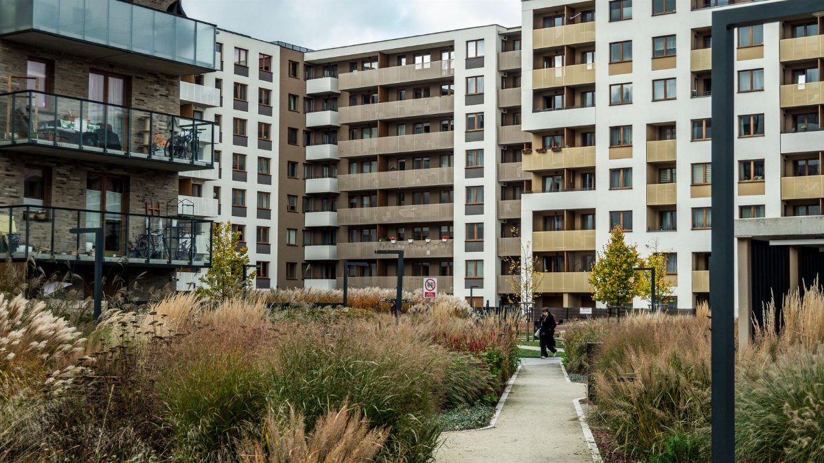 A scenic view of a modern urban apartment complex with landscaped gardens in autumn.