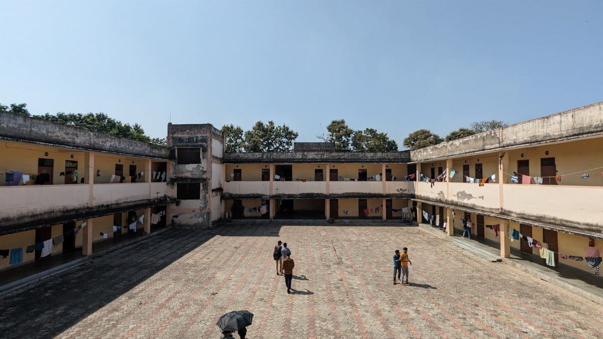 A sunny courtyard with people walking and laundry hanging on balconies under a clear sky.