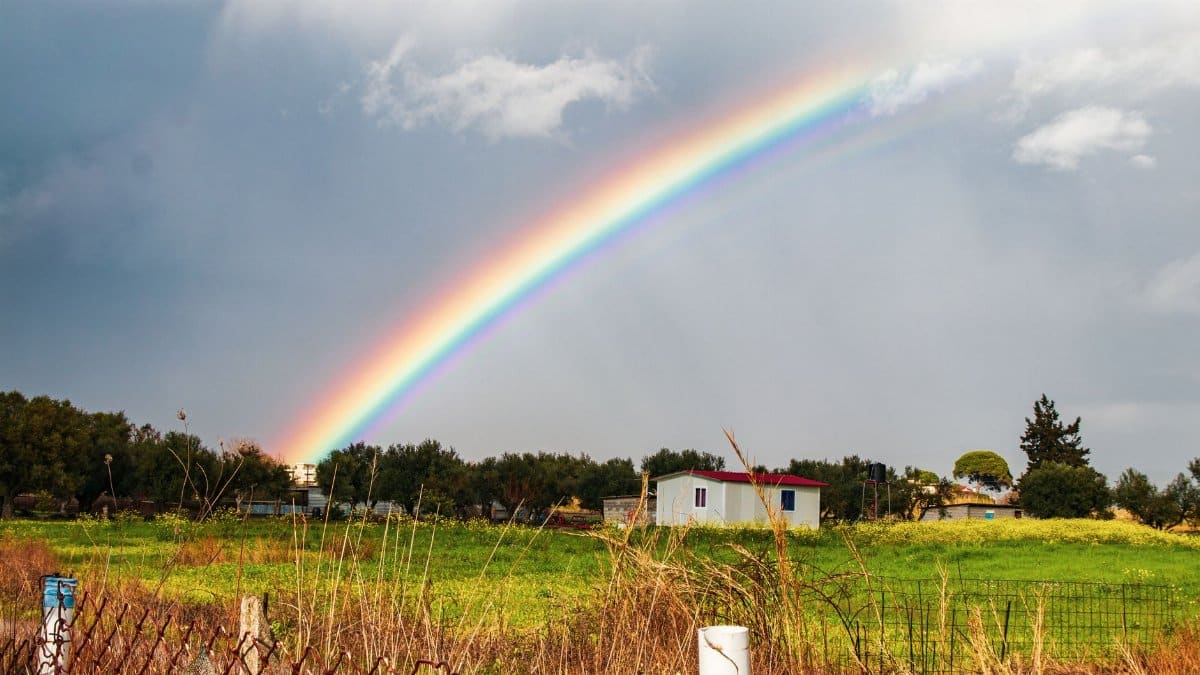 A beautiful rainbow arcs over a rural countryside farm, capturing the essence of nature and tranquility after rain.