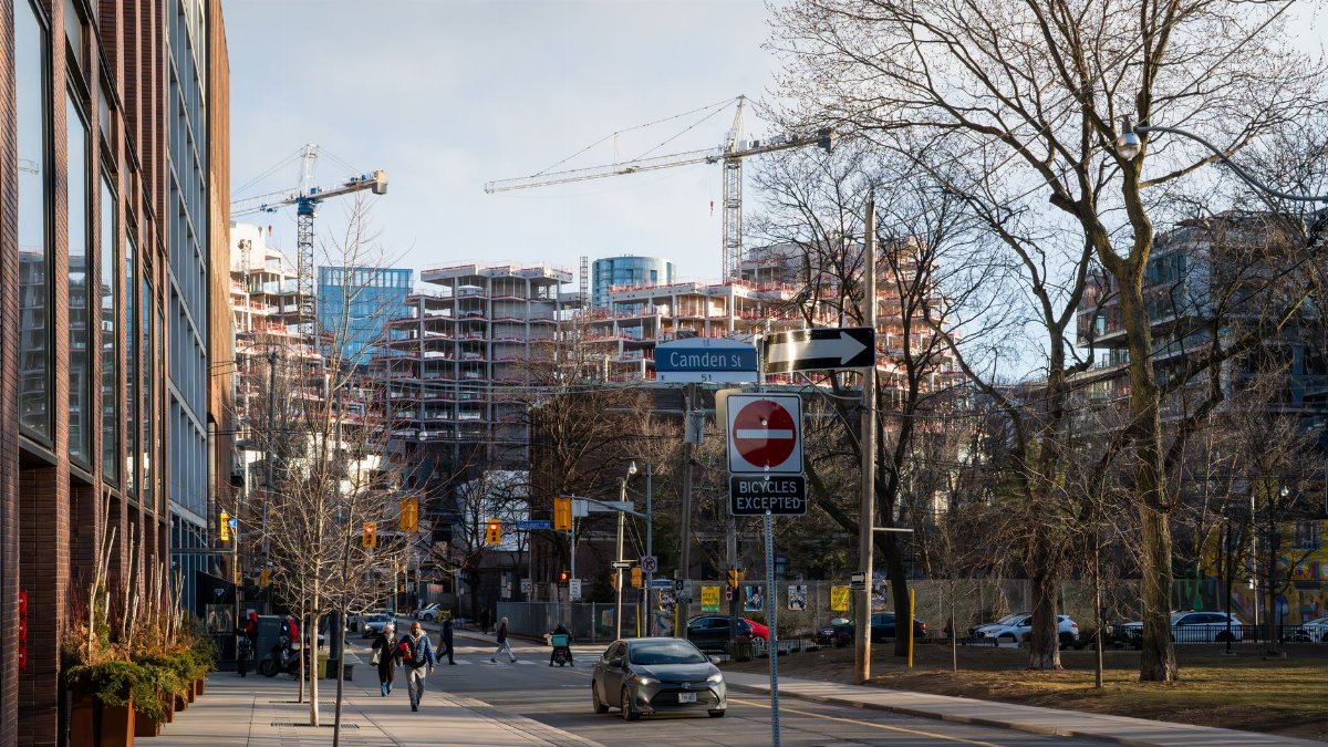 Urban construction site in downtown Toronto with cranes and modern architecture.