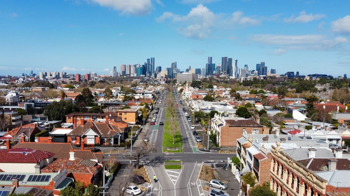 Aerial view of Carlton North neighborhood with Melbourne's skyline under a clear day sky.