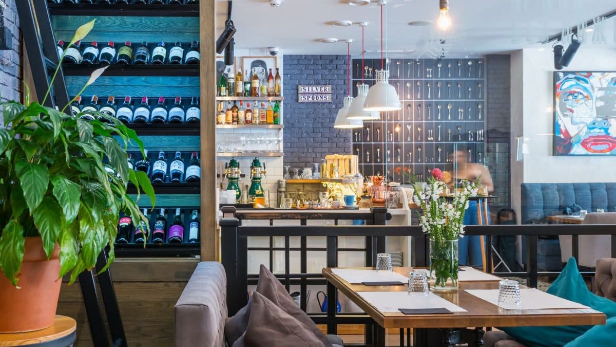 Through glass of contemporary restaurant with soft furniture and various decorative elements on shelves
