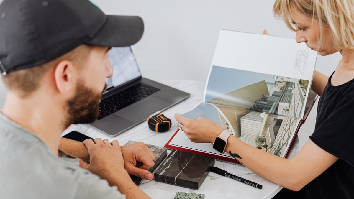 Two interior designers discussing architectural plans in an office setting.