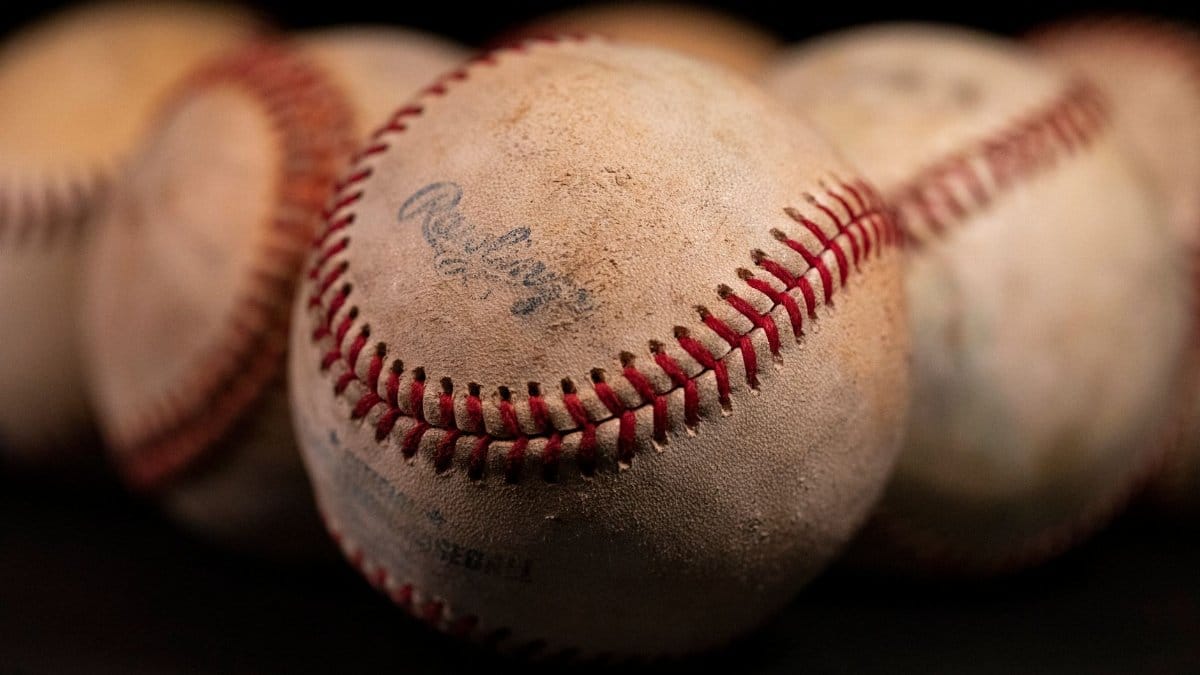 Focused close-up of old baseballs with visible stitching and texture against a dark background.