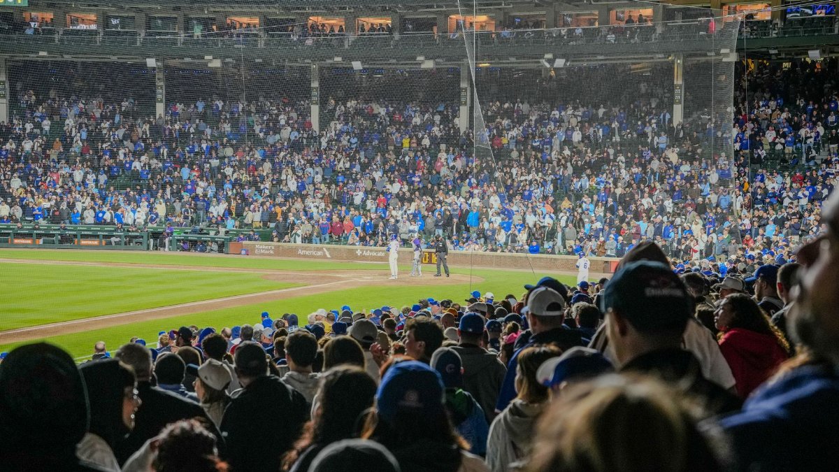 Energetic scene of a nighttime baseball game with a packed stadium crowd.
