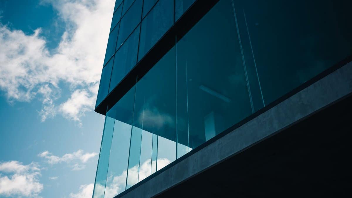 Low angle view of modern glass building against a vibrant blue sky with clouds.