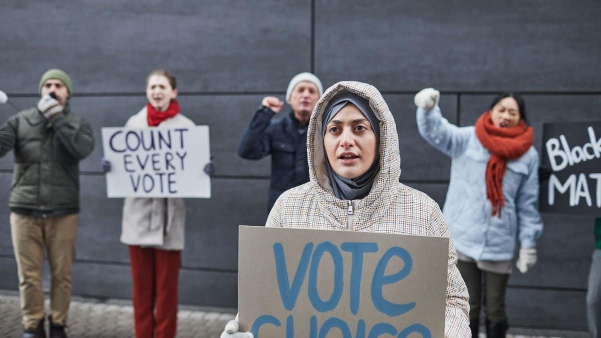 A diverse group of activists protest for voting rights with signs outdoors. Includes signs like 'Vote Choice' and 'Count Every Vote.'