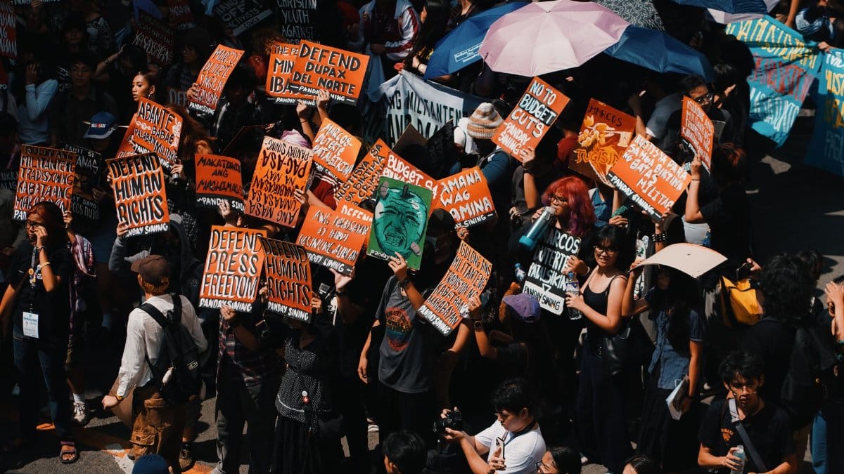 Crowd gathering with colorful signs demanding human rights and freedom in a peaceful protest.