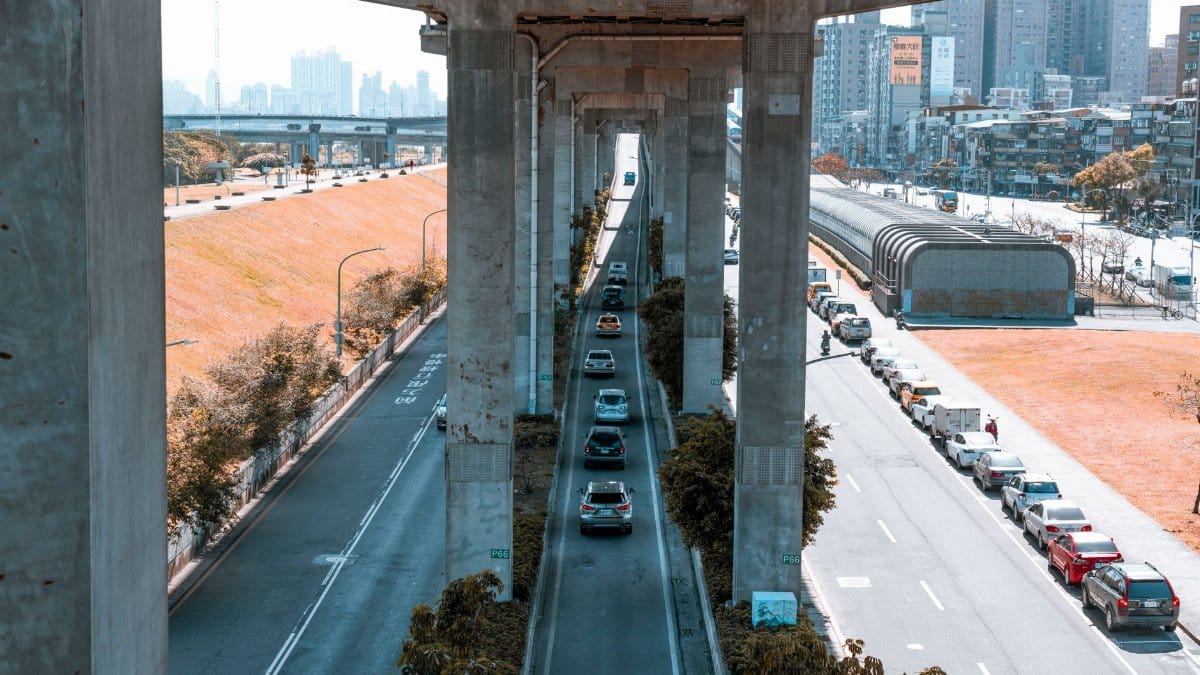 Image of a bustling city street with cars under an elevated road, showcasing urban transportation and infrastructure.