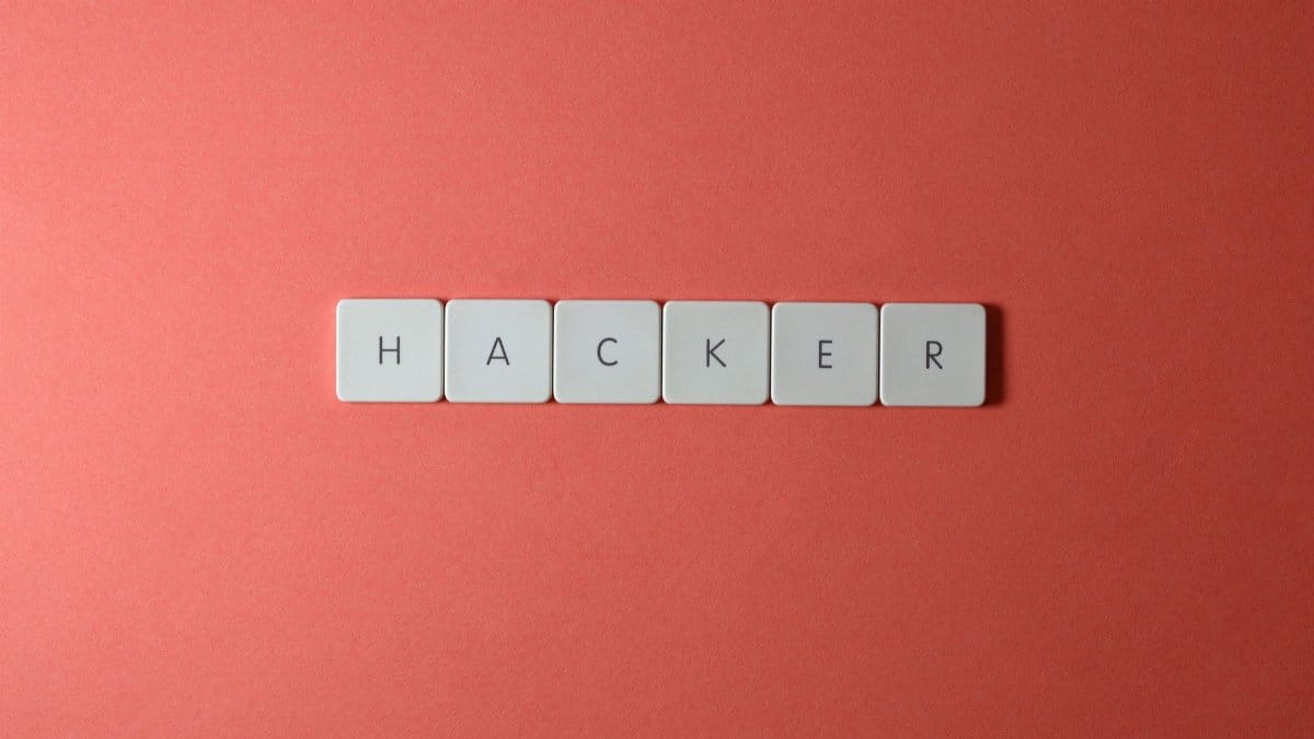 Close-up of the word 'HACKER' made with letter tiles on a red background, emphasizing cybersecurity.