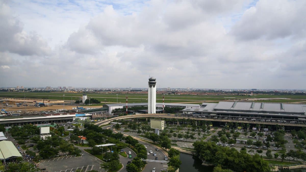 Aerial view of a bustling airport with control tower and surrounding landscape, highlighting infrastructure.