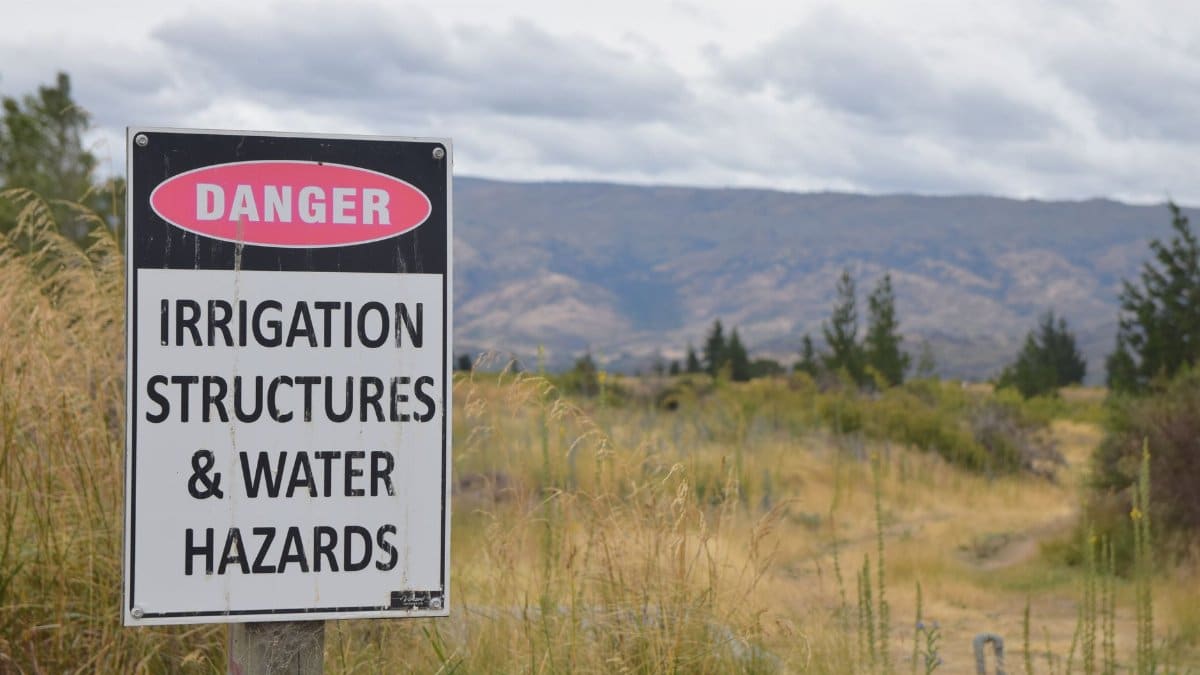 Danger sign warning about irrigation structures and water hazards in rural Otago, New Zealand.