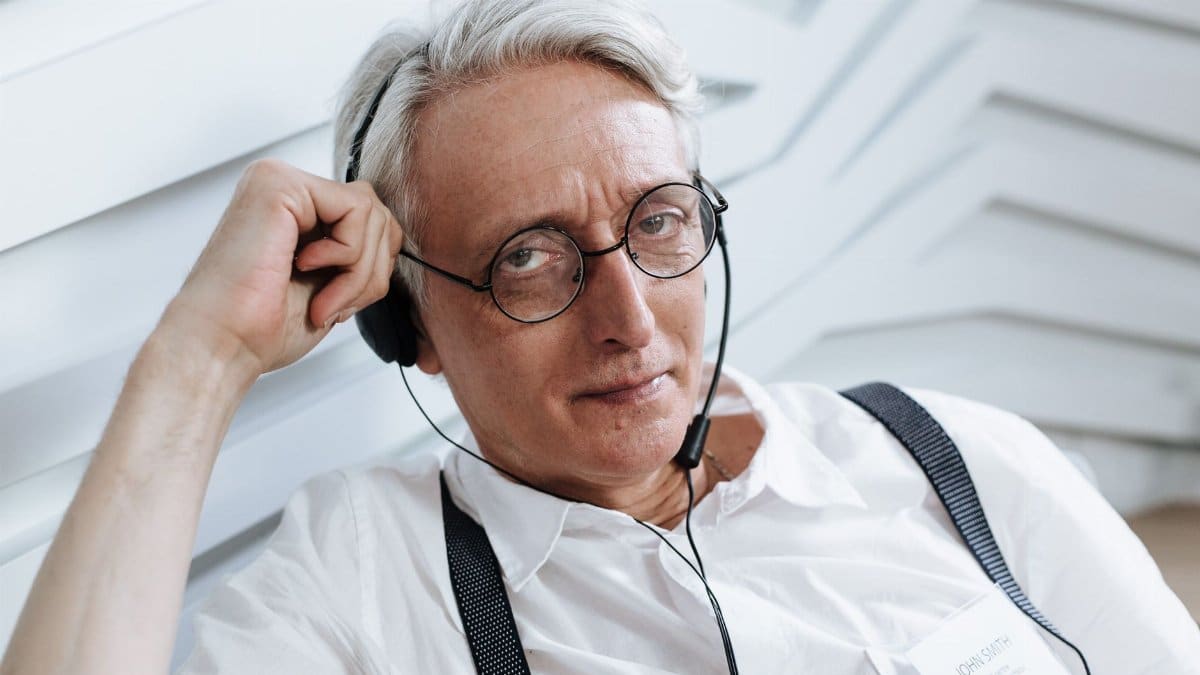 Senior man with glasses and headset working in a customer support role, indoors.