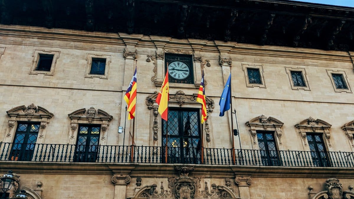 Facade of Palma's City Hall with flags and historic architecture.