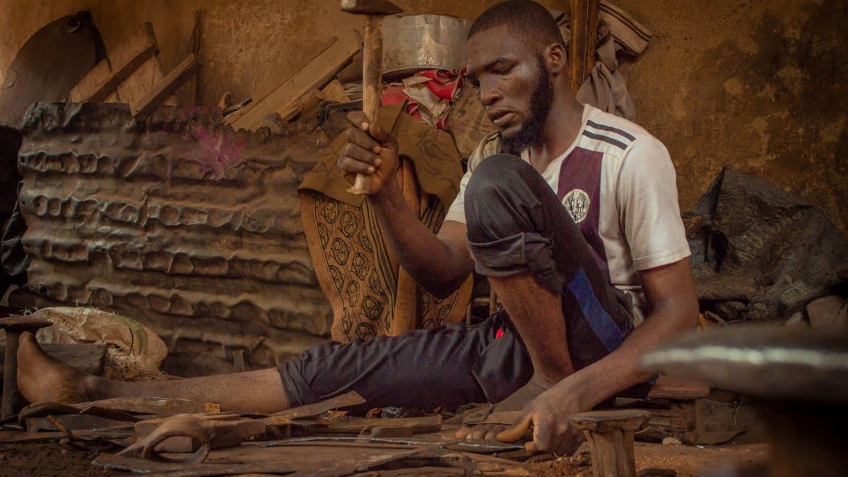 A dedicated blacksmith in Kano skillfully shaping metal using traditional techniques.