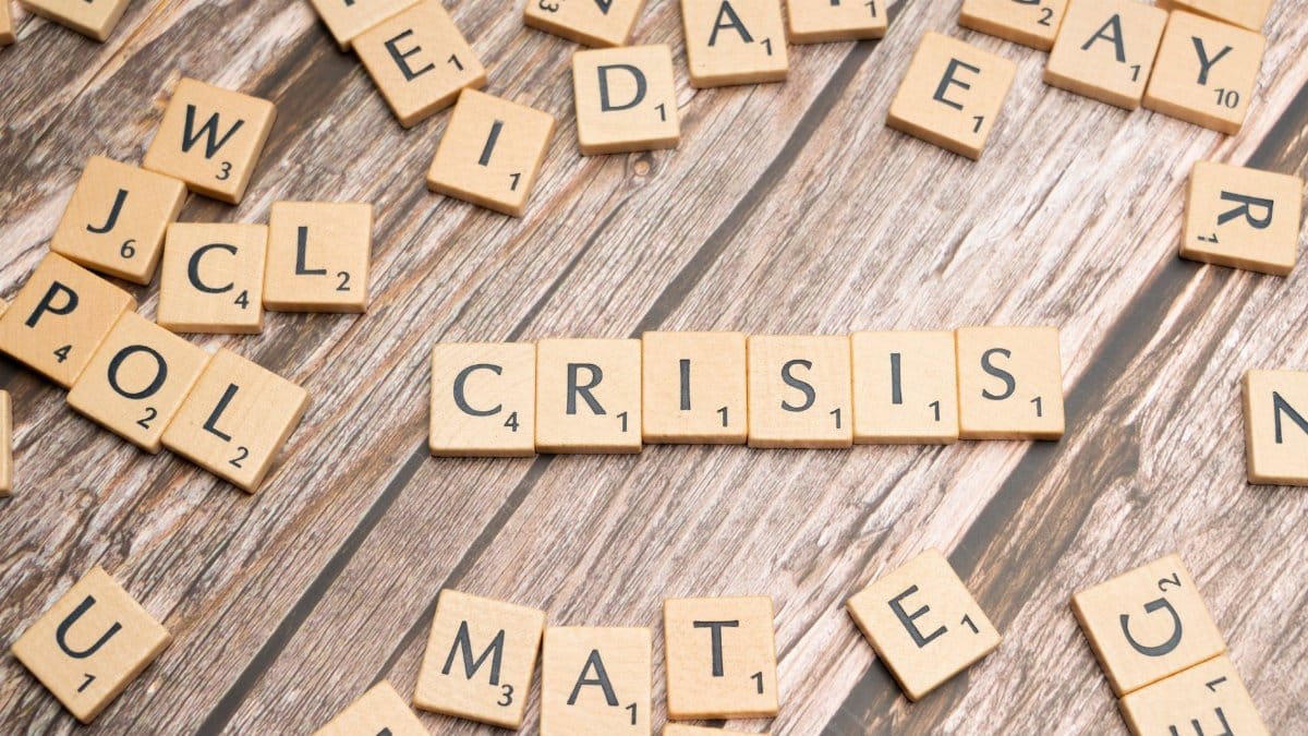 Wooden letter tiles spelling 'Crisis' on a wooden background, conveying a sense of challenge.