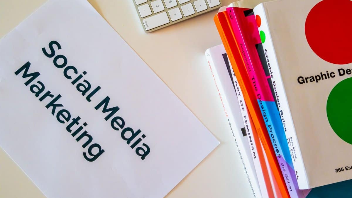 A top view of social media marketing text alongside graphic design books and a keyboard.
