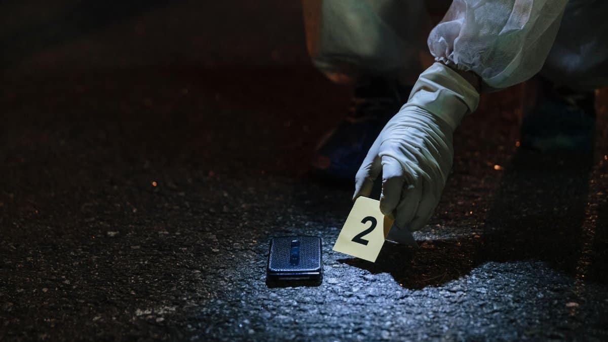 Forensic investigator examining evidence in a city street at night.