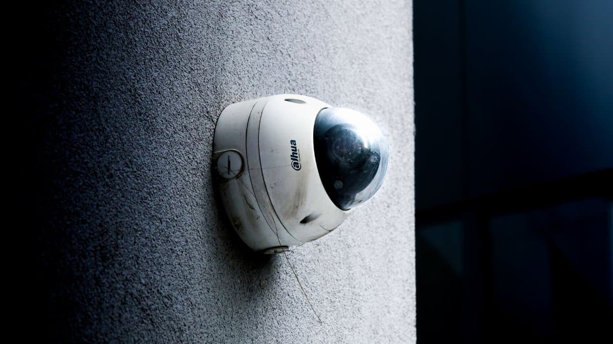 Close-up view of a dome security camera mounted on a concrete wall for surveillance.