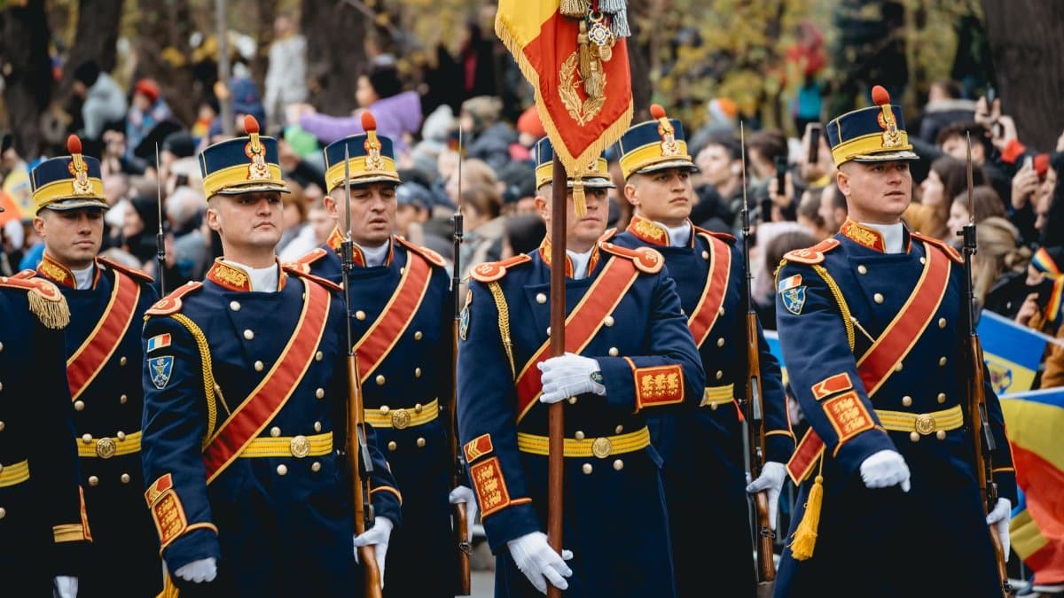 Romanian soldiers in traditional uniforms marching during a parade.