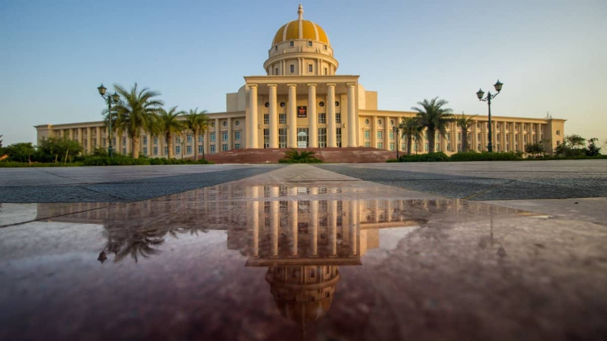 A grand building with architectural columns reflected in a smooth surface.