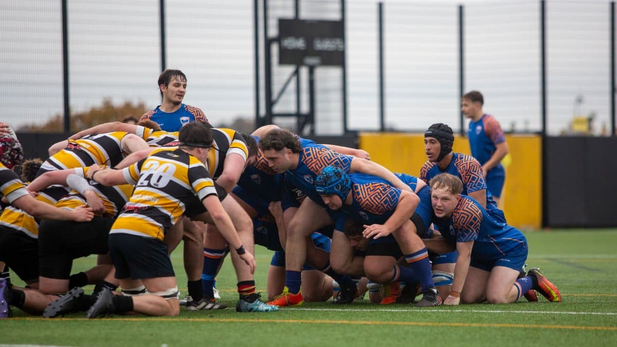 University rugby teams engage in a scrum during a competitive outdoor match.