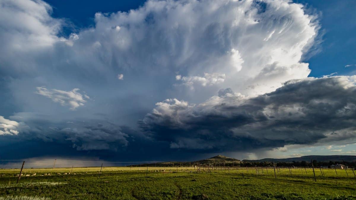 Vast cumulonimbus cloud rises over grassy field in KwaZulu-Natal, South Africa, creating a dramatic landscape.