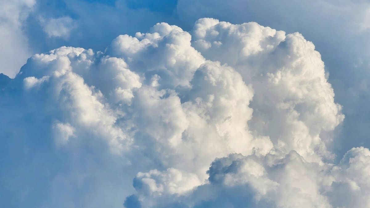 A beautiful view of cumulus clouds floating across a clear blue sky, perfect for weather-themed projects.