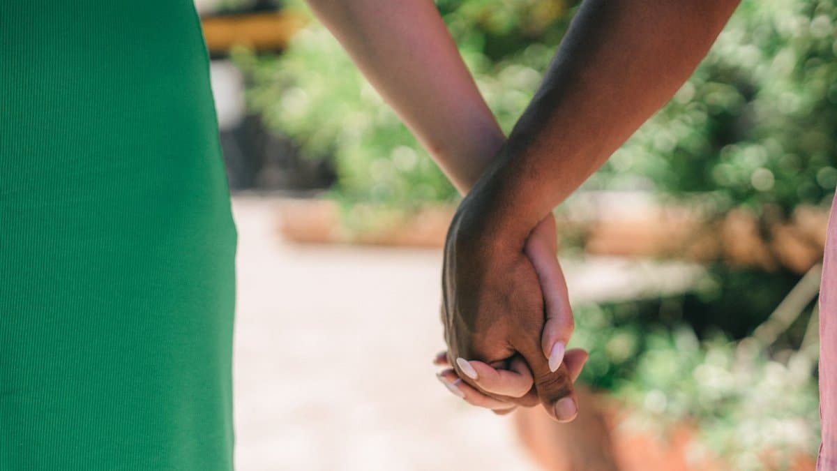 Romantic close-up of a couple holding hands outdoors, symbolizing love and connection.