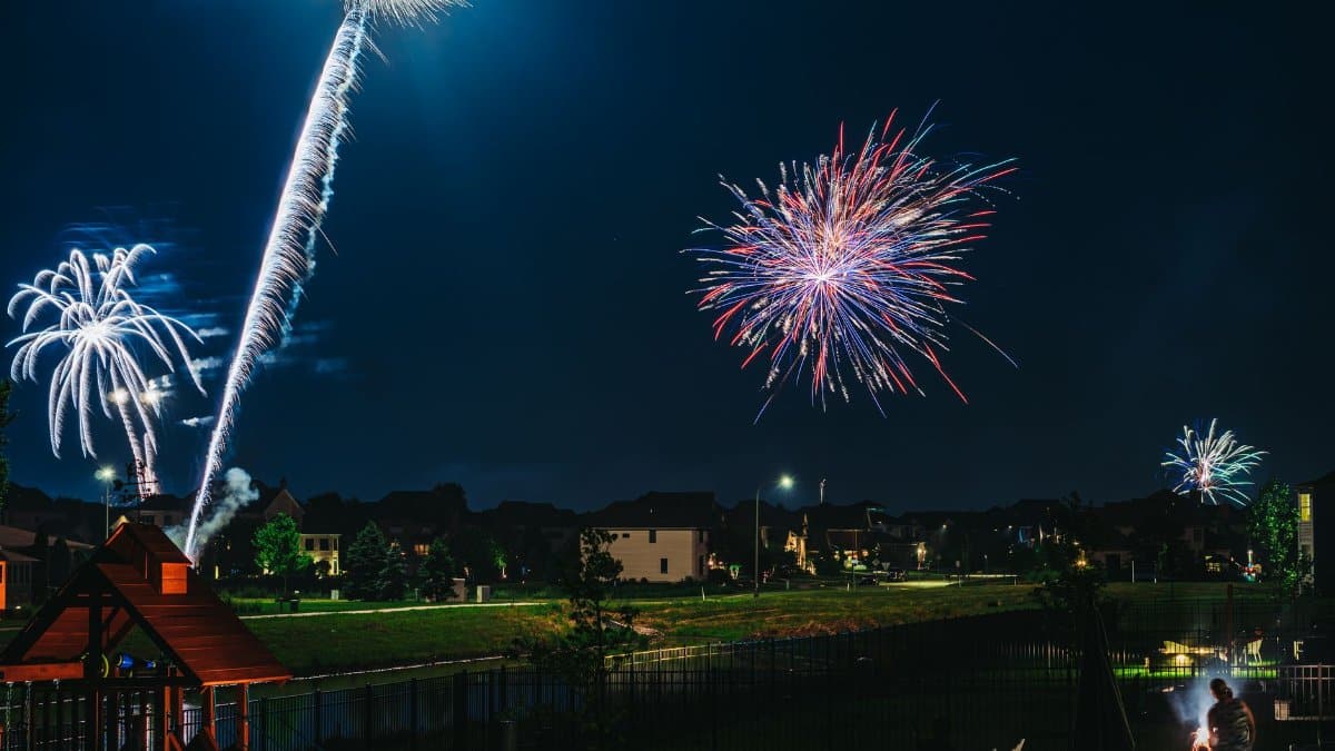 Stunning fireworks light up a suburban neighborhood under a clear night sky, capturing a moment of festive celebration.