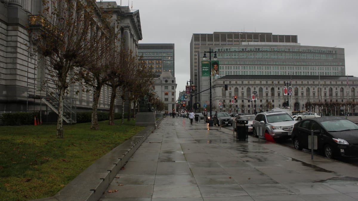 Street view of a rainy day in the city with historical buildings and cars.
