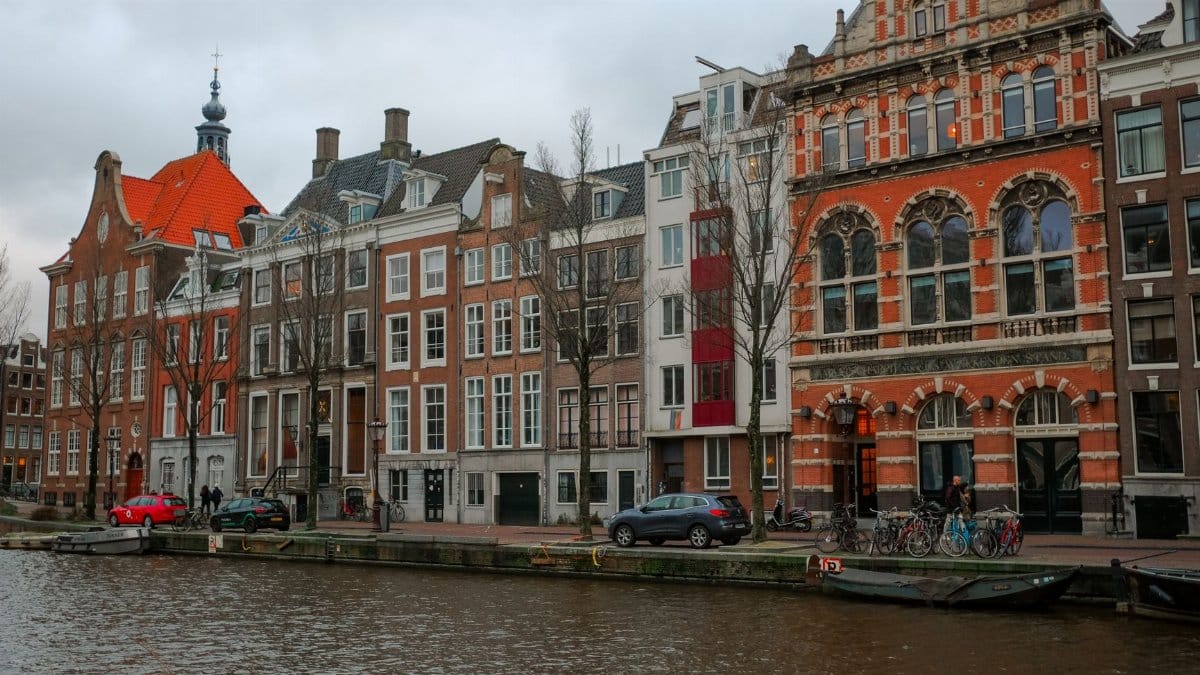 Picturesque Amsterdam canal lined with historic red-brick rowhouses and bikes.