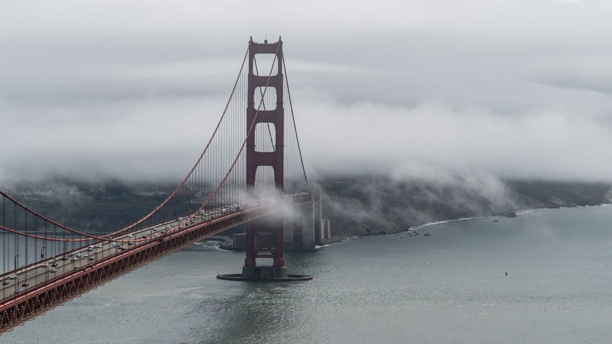 Aerial view of the Golden Gate Bridge enveloped in fog over San Francisco Bay.