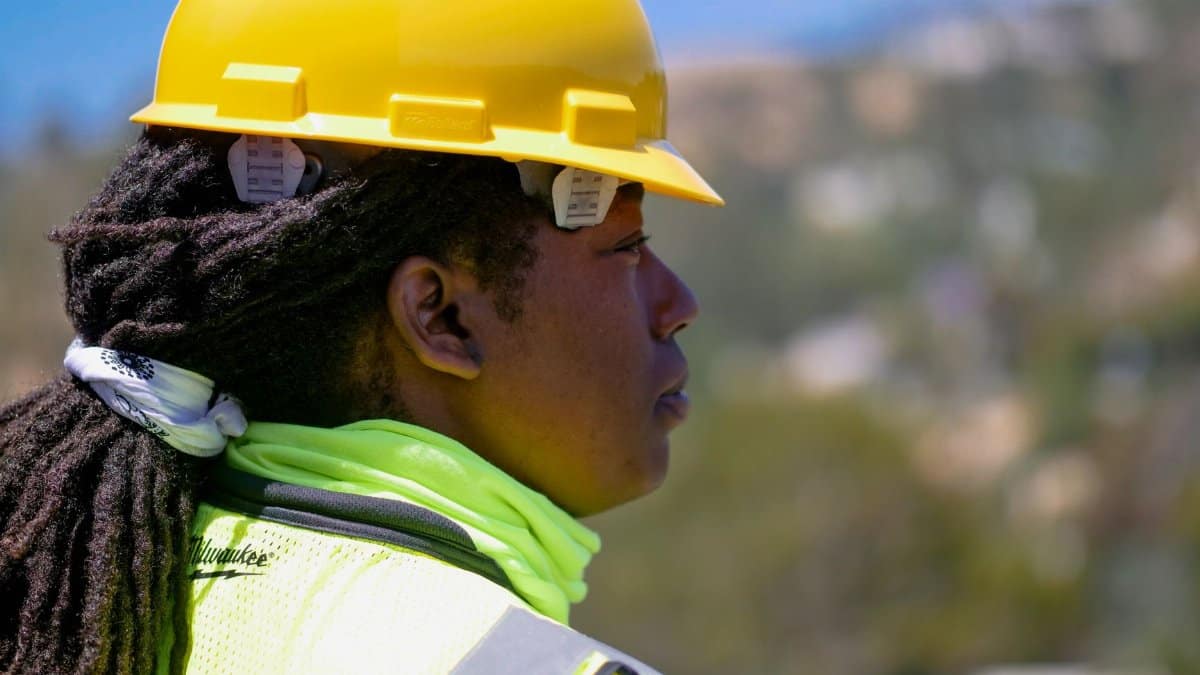 Professional female engineer wearing safety gear and hardhat at a construction site outdoors.