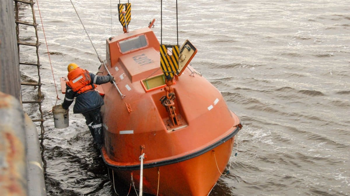A safety drill featuring a person boarding an orange lifeboat at sea.