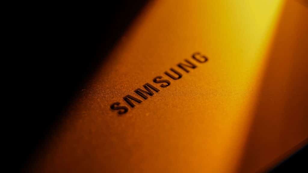 Dramatic close-up of a Samsung electronic device highlighted by golden lighting and shadows.