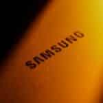 Dramatic close-up of a Samsung electronic device highlighted by golden lighting and shadows.