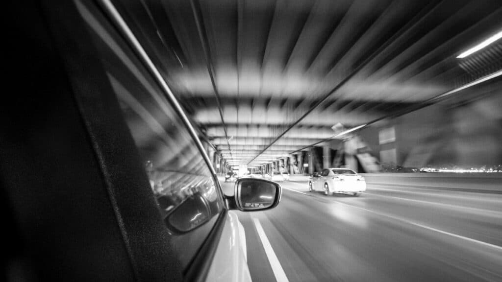 Black and white motion blur shot from a car on a San Francisco bridge at night.