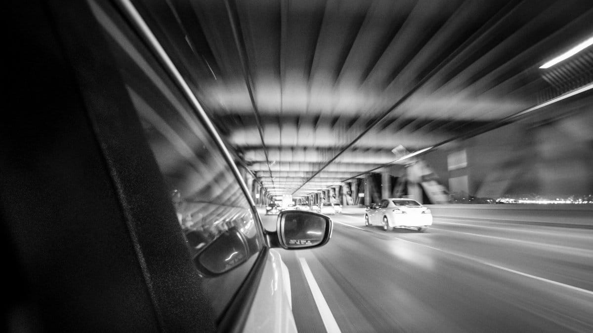 Black and white motion blur shot from a car on a San Francisco bridge at night.