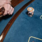 Detailed view of a casino gaming table with poker chips and a wooden pipe on the side.