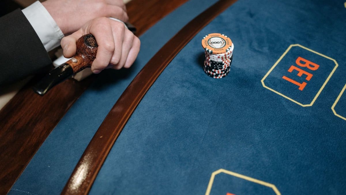 Detailed view of a casino gaming table with poker chips and a wooden pipe on the side.