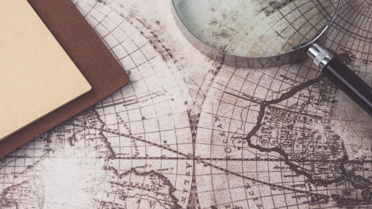 A close-up of a vintage map, magnifying glass, and notebook, perfect for research themes.