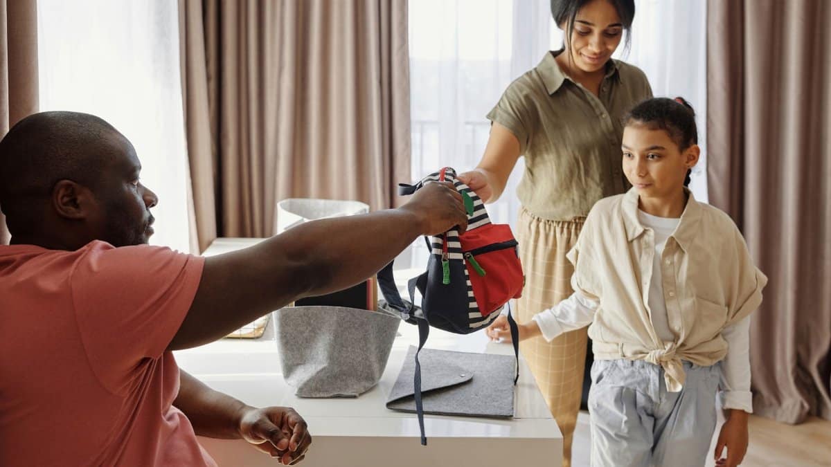 Family helping child get ready for school in a cozy indoor setting.