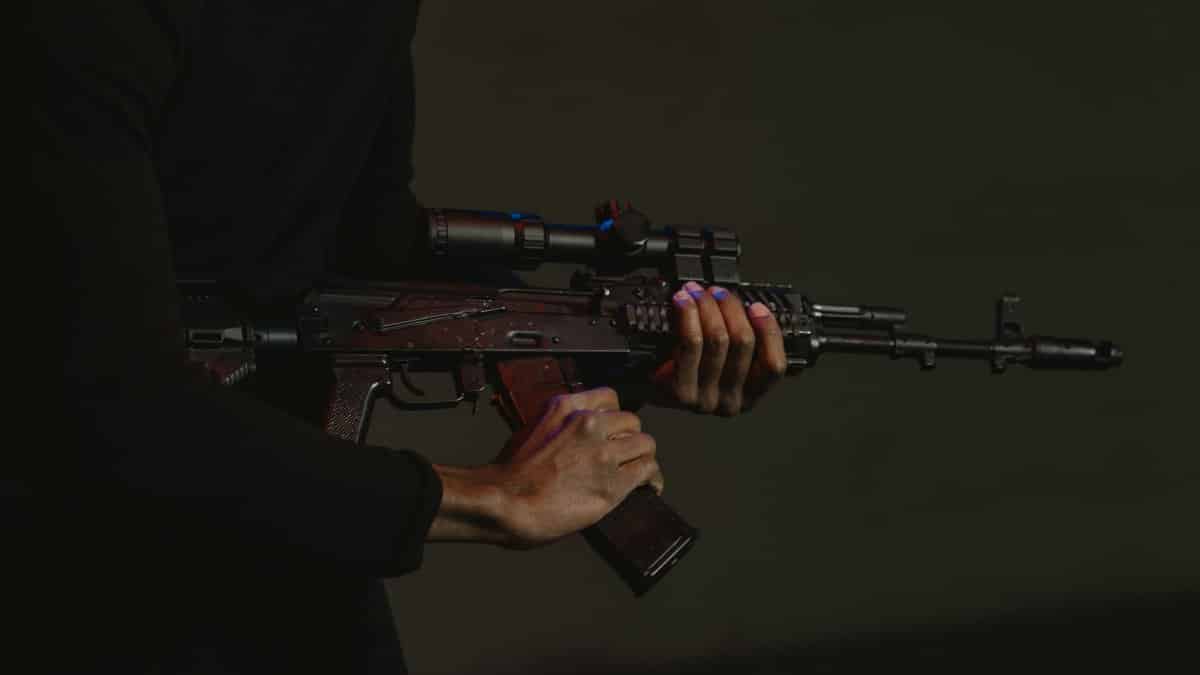 Dramatic image of a person holding a rifle with a scope, taken in low light.