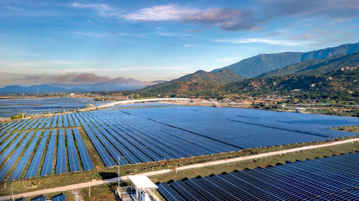Expansive solar panels in a scenic landscape with mountains, demonstrating renewable energy efforts.