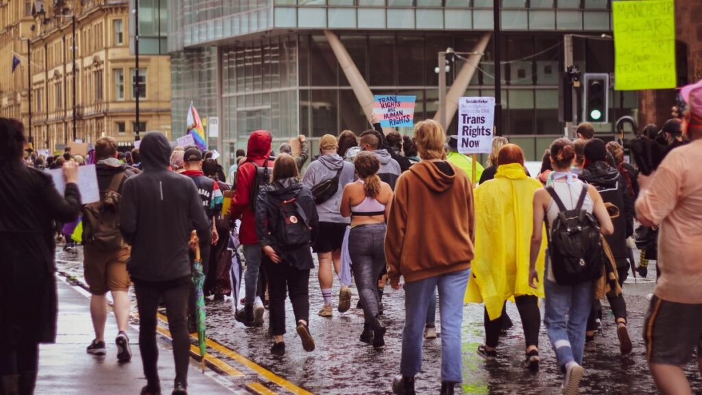 A large group peacefully protests for trans rights in a city, advocating equality.