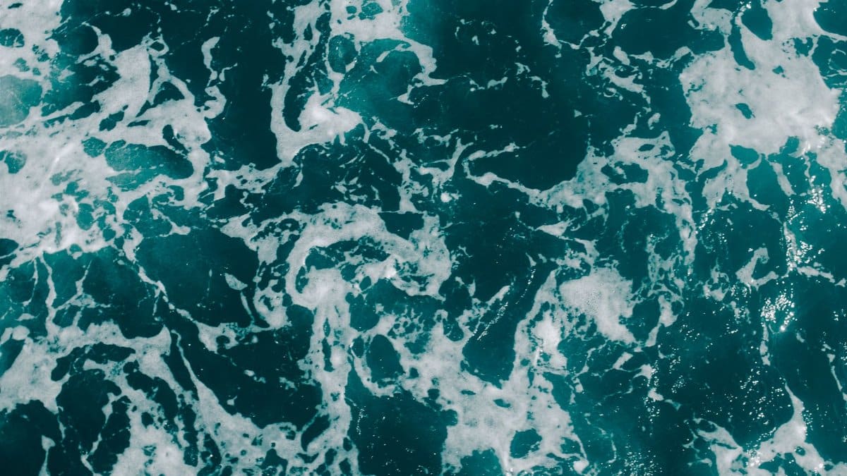 Dynamic aerial photograph of ocean waves with foamy textures, showcasing sea patterns.