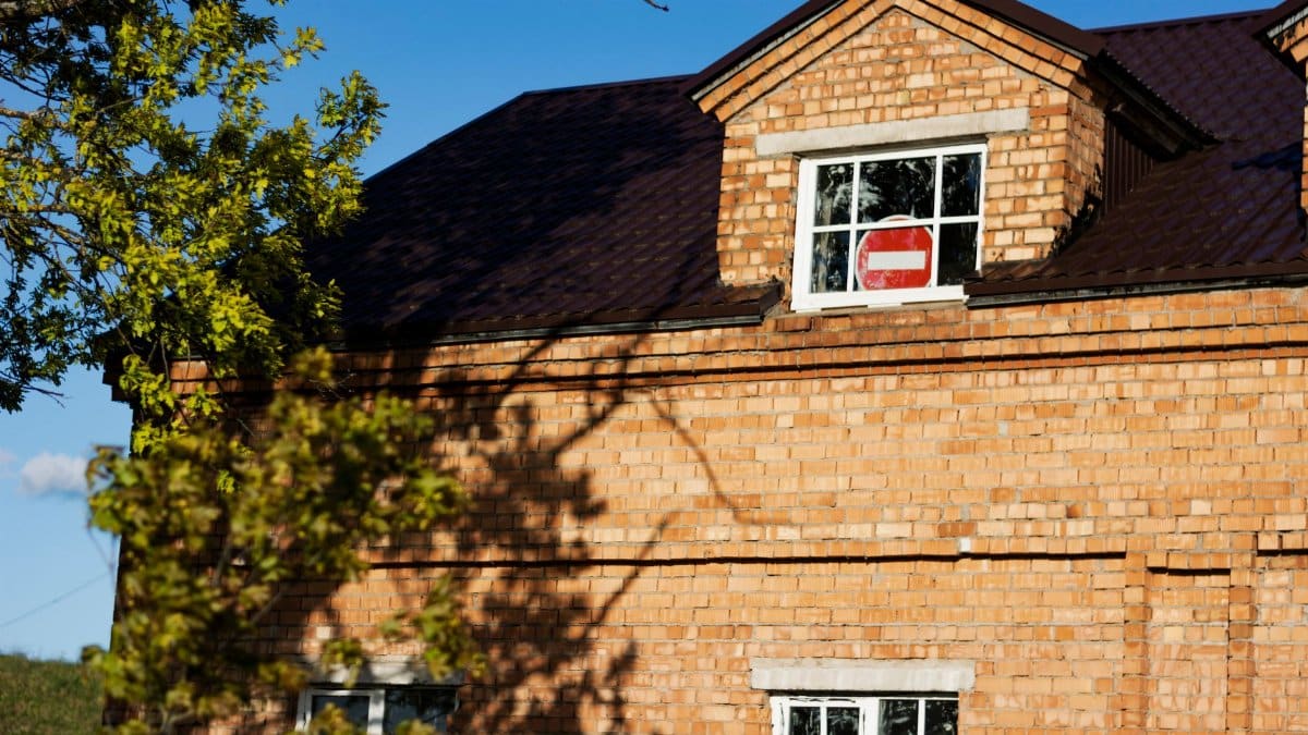 Close-up of a red brick house exterior featuring a no entry sign in a window.